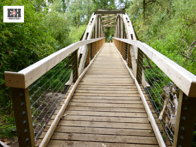 Timber bridge with wooden planks and wire railings, surrounded by lush greenery, illustrating E&H Manufacturing's commitment to preserving Charleston's heritage.