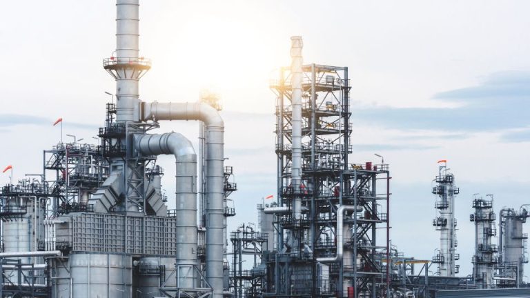 Oil and gas industrial facility with large machinery, pipes, and structures, emphasizing safety and operational efficiency in extraction processes.