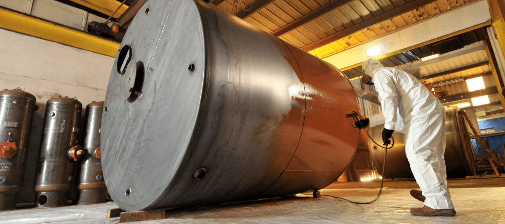 Photo of a man adding a protective coating onto a custom made steel holding tank